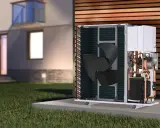 Unidad exterior de bomba de calor para hidrotermia en casa, con ventilador y tuberías de cobre visibles, junto a una casa moderna.