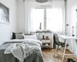Chambre 10m2 lumineuse avec lit confortable, bureau et fenêtre. Un cactus sur le rebord de fenêtre ajoute une touche de verdure.