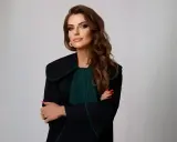 Kobieta w todze prawniczej, z rękami skrzyżowanymi na piersi, na jasnym tle.