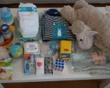 Zestaw zawiera przekąski do samolotu dla dziecka: chrupki, słoiczki, pieluchy, chusteczki, butelki, ubranko i pluszaka.