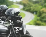 Gotowe na przygodę? Zastanawiasz się nad prawem jazdy na motor i wiekiem? Dwa kaski czekają na motocyklistów na krętej drodze.