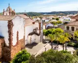 Blick über die weißen Häuser und Palmen von Silves, Portugal, mit einer Kirche im Vordergrund.