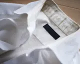 Biała koszula z widocznymi żółtymi plamami od potu na kołnierzyku. Dowiedz się, jak usunąć żółte plamy z potu z białej koszuli.