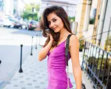 Chica sonriente con vestido buganvilla y maquillaje natural, paseando por la ciudad.