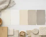 Palette de couleurs douces : échantillons de peinture écru et blanc cassé, bois, pierre et tissu texturé.