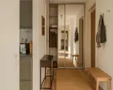 En ljus hall med spegelskjutdörrar, en smal konsol, en träbänk och en matta. Perfekt hall inspiration för en funktionell och stilren entré.