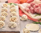 Gotowe do lepienia pierogi z mięsem mielonym surowym. Na desce ułożone pierożki, obok surowe mięso i ciasto.