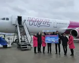 Grupa osób pozuje przed samolotem Wizz Air, trzymając tablicę z informacją o nowych trasach, w tym lotach Szczecin-Bergen.