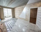 Habitación en construcción con suelo de mármol y sistema de calefacción por suelo radiante. El alicatado que es, se ve en el suelo y en la pared.