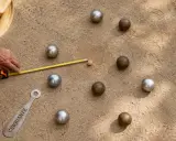 Un joueur mesure la distance entre le cochonnet et les boules lyonnaises. La règle du jeu est respectée.