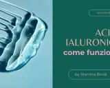 Goccia di acido ialuronico trasparente su sfondo azzurro, con testo "Acido Ialuronico: come funziona?".