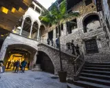 Gente paseando por un patio interior con palmera, escaleras de piedra y arcos. Ideal para visitar museos gratis domingo Barcelona.