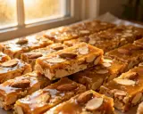 Délicieuses barres de nougatine recette, garnies d'amandes entières et effilées, sous une lumière douce.