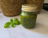 Un pot de pesto maison, vert vif, à côté de feuilles de basilic frais. Parfait pour sublimer vos plats !