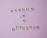 Litery układają napis "GENDER IS A SPECTRUM", podkreślając, że dysforia i niezgodność płciowa są częścią szerokiego spektrum tożsamości.