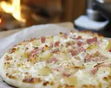 Flammekueche traditionnelle avec lardons et pommes de terre, prête à être dégustée près du feu.