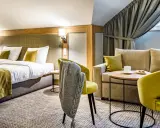 Przytulny pokój hotelowy z dwoma łóżkami, kanapą i fotelami. Idealne miejsce na relaks po podróży.