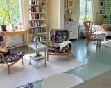 Ljust och luftigt vardagsrum med två färgstarka fåtöljer, bokhyllor och en soffgrupp. En harmonisk känsla som påminner om feng shui vardagsrum.