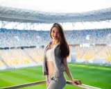 Uśmiechnięta dziewczyna w sportowym stroju na tle stadionu. Idealny pomysł, jak się ubrać na mecz, by czuć się komfortowo i stylowo.