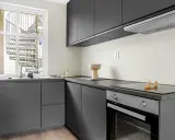 Diseño cocina restaurante moderno con gabinetes grises, encimera oscura y ventana con escalera exterior.