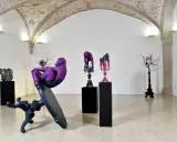 Sculture di scimmie e cervi colorati, opere di **artisti contemporanei famosi**, in una galleria con affreschi sul soffitto.