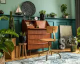 Wnętrze w stylu retro: drewniane biurko, krzesło, rośliny i dekoracje tworzą przytulną atmosferę.