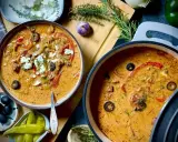 Zwei Töpfe mit cremiger Gyrossuppe, garniert mit Feta, Oliven und Paprika. Ein köstliches Gyrossuppe Rezept für kalte Tage.