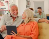 Uśmiechnięci seniorzy przeglądają tablet, obok nich logo "Karta Seniora Ogólnopolska", sugerujące zniżki w aptece.