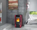 Estufa de leña o pellets roja con fuego encendido, junto a una estantería blanca y un sillón curvo.