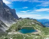 Lago di Coldai, incastonato tra le maestose vette delle Dolomiti, con sentieri che si snodano sui prati verdi.