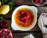 Creme Brulee mit Himbeeren und Granatapfelkernen. Dazu passen Zitronen und Zucker.