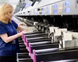 Pracownica Poczty Polskiej wykonuje sortowanie przesyłek na taśmie.