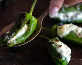 Grön paprika fylld med ost, som pimientos de padron, ligger på en sked.