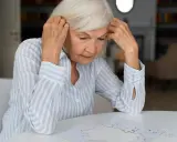 Starsza kobieta z problemami z pamięcią próbuje ułożyć puzzle, zdezorientowana.