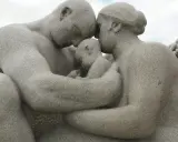 Kamienna rodzina w parku w Oslo, czułe objęcia rodziców otulających dziecko.