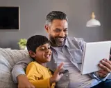 Ojciec i syn śmieją się, oglądając tablet. To idealny dzień wolny za święto w sobotę, spędzony razem na zabawie.