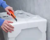Ręce tnące nożem opakowanie ze styropianu.