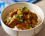 Aksamitny kurczak w sosie curry, podany na białym ryżu, z gałązkami kolendry. Idealny prosty przepis na obiad.
