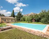 Piscina in un casale in pietra nel Val d'Orcia, Italia, con un borgo medievale sullo sfondo.