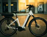 Biały rower elektryczny Romet z bagażnikiem i sakwą, gotowy na rower elektryczny duży zasięg.