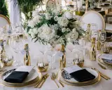 Eleganckie dekoracje sali weselnej glamour: złote akcenty, białe kwiaty i buteleczki szampana tworzą luksusową atmosferę.