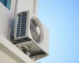 Unidad exterior de aire acondicionado montada en la pared de una terraza cerrada, lista para refrescar el ambiente.