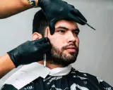 Barber precyzyjnie goli zarost brody ostrym narzędziem.