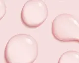 Gocce rosa su sfondo rosa, simili a quelle che si trovano in prodotti con cetearyl alcohol cos'è, un ingrediente emolliente.