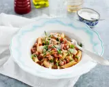 En tallrik med penne pasta, kyckling och tärnad pancetta, toppad med persilja och parmesan. Ett enkelt pancetta recept för en god middag.