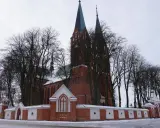 Zimowy dzień przy kościele Garbów. Czerwona cegła, wysokie wieże i nagie drzewa tworzą malowniczy widok.