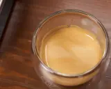Ein Glas Espresso mit einer feinen Crema auf einem Holztisch. Ein kleiner Schuss Sahne macht den Kaffee mit Sahne gesund und lecker.