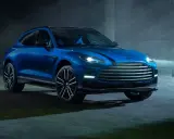 Niebieski Aston Martin DBX 707 lśni w mrocznym, industrialnym otoczeniu.