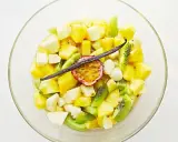 Salade de fruits tropicaux coupés en dés dans un bol en verre, garnie de fruits de la passion et d'une gousse de vanille.