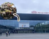 Besucher strömen zur Intermodellbau Messe in Dortmund. Ein kleiner Kreis zeigt die belebte Halle mit vielen Ausstellungsstücken.
